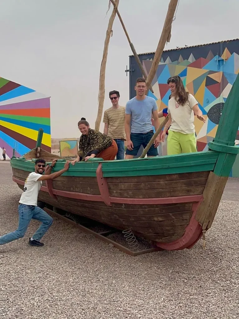 A group of tourists enjoying a movie set tour with a professional travel agency in Morocco and their guide on a vintage boat in Ouarzazate.